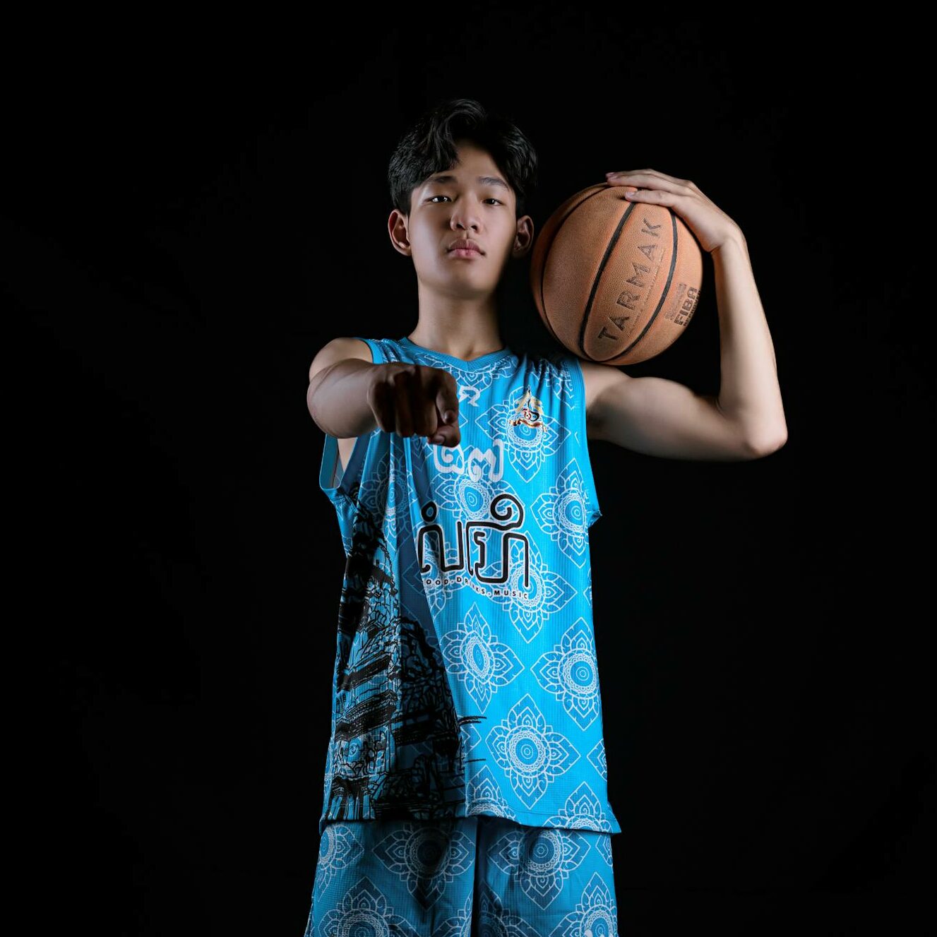 Dynamic portrait of a young basketball player posing with a ball in a studio setting.