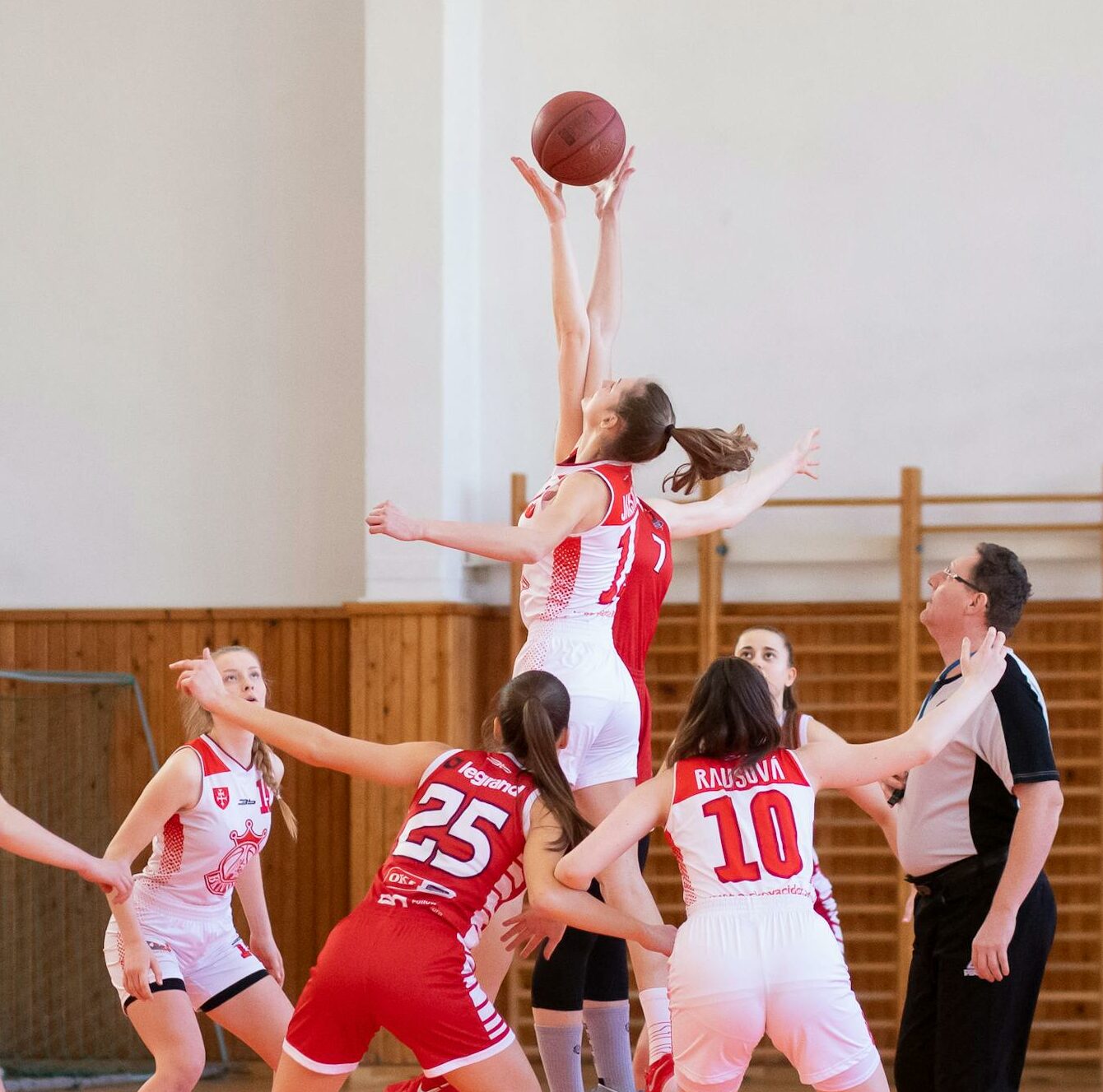 Exciting women's basketball game in a school gym, showcasing teamwork and athleticism.